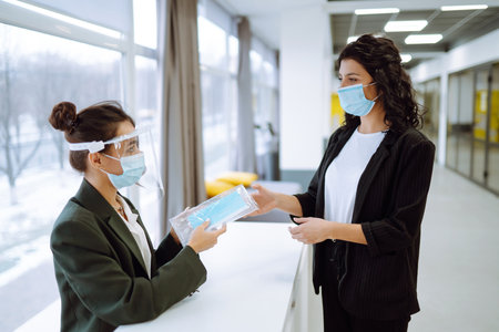 Two business colleagues in protective face mask discussing work related matters on an office.の写真素材