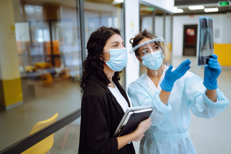 Two business colleagues in protective face mask discussing work related matters on an office.の写真素材