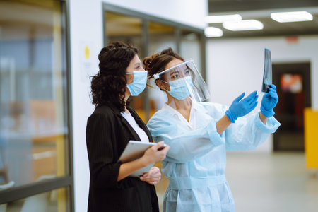 Two business colleagues in protective face mask discussing work related matters on an office.の写真素材