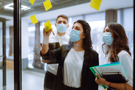 Business team people in protective face mask brainstorm on corporate project together write strategyの写真素材