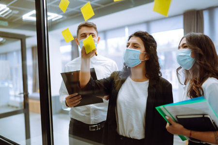 Office worker wearing face mask for social distancing for virus prevention while using laptop.の写真素材