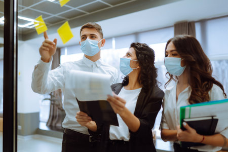 Office worker wearing face mask for social distancing for virus prevention while using laptop.の写真素材