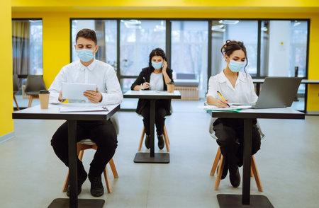 Office worker wearing face mask for social distancing for virus prevention while using laptop.の写真素材