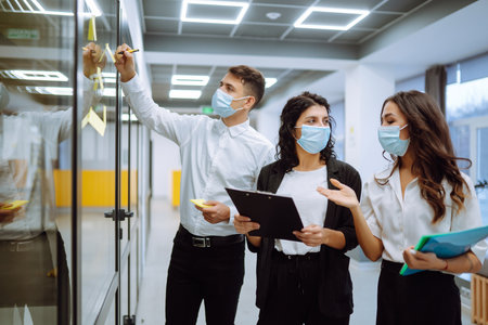 Office worker wearing face mask for social distancing for virus prevention while using laptop.の写真素材