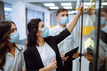 Office worker wearing face mask for social distancing for virus prevention while using laptop.の写真素材