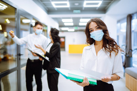 Office worker wearing face mask for social distancing for virus prevention while using laptop.の写真素材