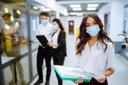 Office worker wearing face mask for social distancing for virus prevention while using laptop.の写真素材