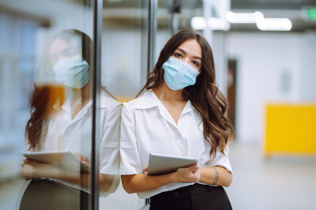 A female doctor in visor and protective gloves examines an X-ray of a patientの写真素材