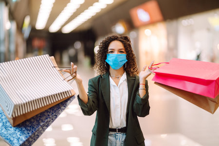 Young woman wearing protection face mask against coronavirus after shopping in the mall. Covid-2019.の写真素材