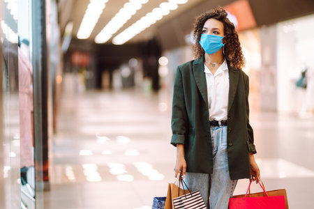 Young woman wearing protection face mask against coronavirus after shopping in the mall. Covid-2019.の写真素材