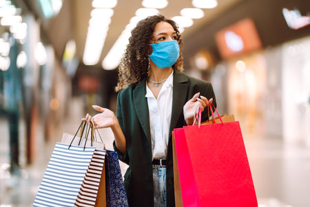 Young woman wearing protection face mask against coronavirus after shopping in the mall. Covid-2019.の写真素材
