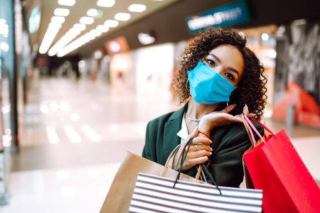 Young woman wearing protection face mask against coronavirus after shopping in the mall. Covid-2019.の写真素材