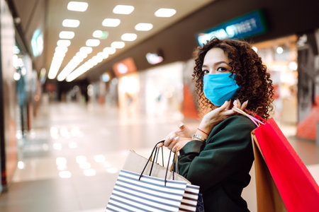 Young woman wearing protection face mask against coronavirus after shopping in the mall. Covid-2019.の写真素材