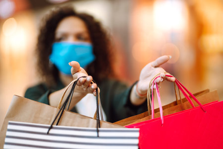 Young woman wearing protection face mask against coronavirus after shopping in the mall. Covid-2019.の写真素材
