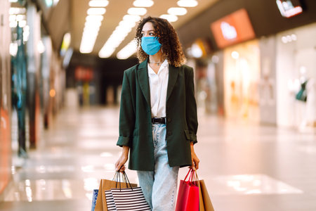 Young woman wearing protection face mask against coronavirus after shopping in the mall. Covid-2019.の写真素材