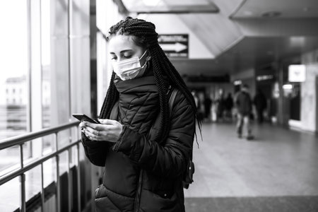 Girl in protective sterile mask on her face with a phone in quarantine city. woman using the phone.の写真素材