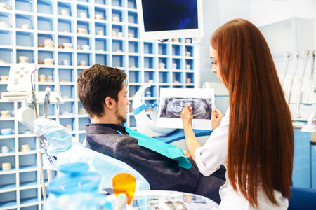Professional woman dentist doctor working. Man at dental clinic. man at dentist taking care of teeth.の写真素材