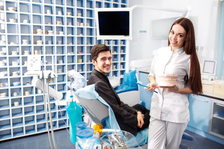 Professional woman dentist doctor working. Man at dental clinic. man at dentist taking care of teeth.の写真素材