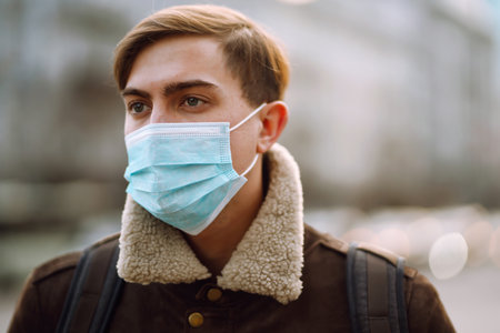 Portrait of men in protective sterile medical mask on her face on the street city. Covid-19.の写真素材