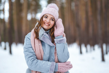 Cute young woman is playing with snow in the forest. Winter lifestyle happiness emotions nature.の写真素材