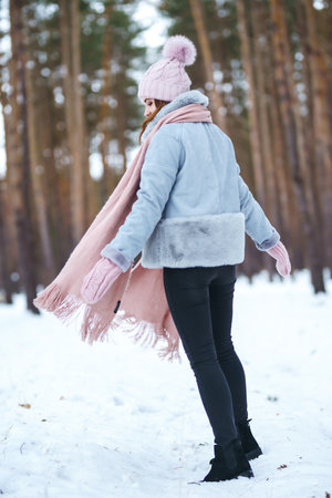 Cute young woman is playing with snow in the forest. Winter lifestyle happiness emotions nature.の写真素材