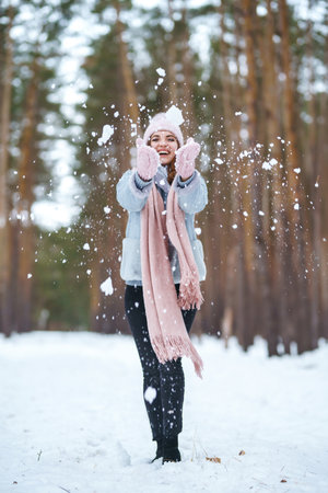 Cute young woman is playing with snow in the forest. Winter lifestyle happiness emotions nature.の写真素材