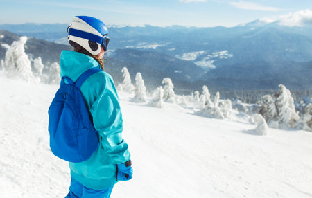 Girl in winter clothes drinking tea on the background of snow-capped mountains on the sunny day.の写真素材
