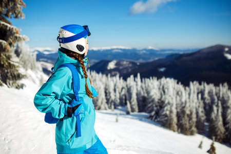 Girl in winter clothes drinking tea on the background of snow-capped mountains on the sunny day.の写真素材