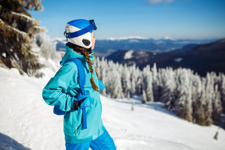 Girl in winter clothes drinking tea on the background of snow-capped mountains on the sunny day.の写真素材