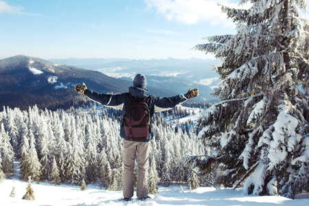 Man with backpack trekking in mountains. Cold weather, snow on hills. winter hiking.の写真素材