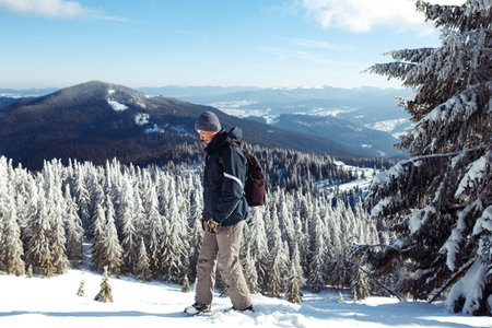 Man with backpack trekking in mountains. Cold weather, snow on hills. winter hiking.の写真素材