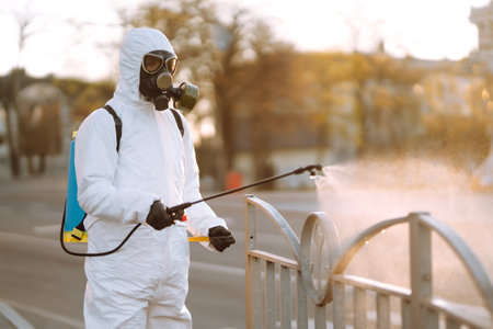 A man wearing special protective disinfection suit sprays sterilizer in the public place. Covid-19.の写真素材