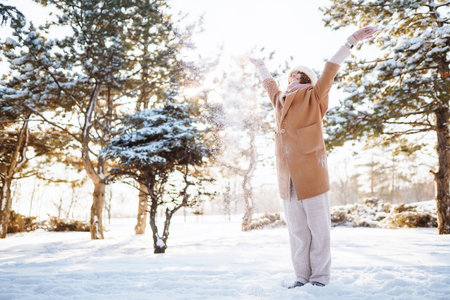 Happy woman walking in the snowy winter day outdoor. Winter fashion, holidays, rest, travel concept.の写真素材