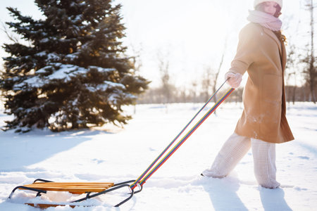 Happy woman walking in the snowy winter day outdoor. Winter fashion, holidays, rest, travel concept.の写真素材