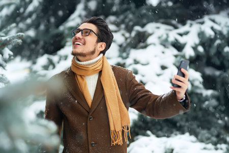 Outdoor close up portrait of young beautiful men. Smiling young man having fun outdoors. snowfall.の写真素材