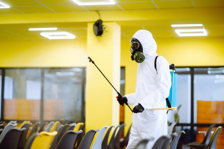 Cleaning and disinfection of office to prevent COVID-19, Man in protective hazmat suit washes officeの写真素材