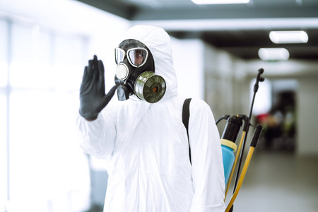 Cleaning and disinfection of office to prevent COVID-19, Man in protective hazmat suit washes officeの写真素材