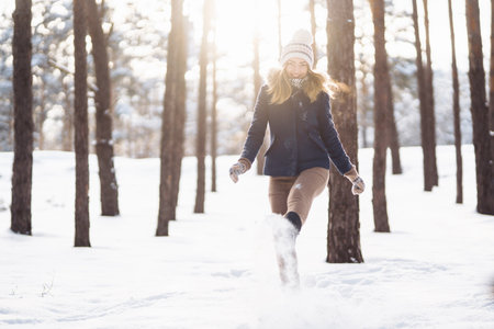 Happy young woman plays with a snow in sunny winter day. Girl enjoys winter, frosty day.の写真素材