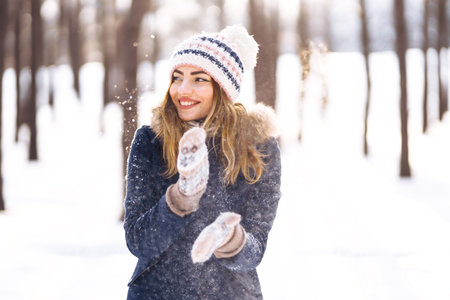 Happy young woman plays with a snow in sunny winter day. Girl enjoy winter, frosty day. playing with snow.の写真素材