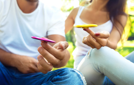 Young girl and boy playing with a fidget spinner in the park. stress relief toy. Sunny summer day.の写真素材