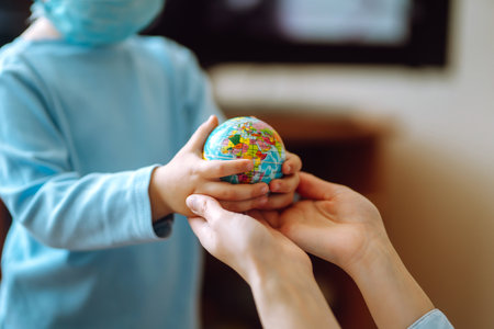 Little son in protective sterile medical mask congratulations mother and gives a bouquet of flowers tulips.の写真素材