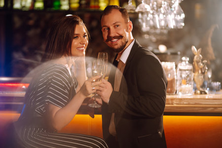 Young Man and woman clinking glasses of champagne at party. Happy loving couple at the bar.の写真素材