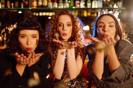Three young Woman with champagne glasses at night club. Women friends drinking champagne in the bar.の写真素材
