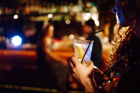 cocktail party. ?ocktail in the hands of a woman. Young woman drinking cocktails in bar.の写真素材