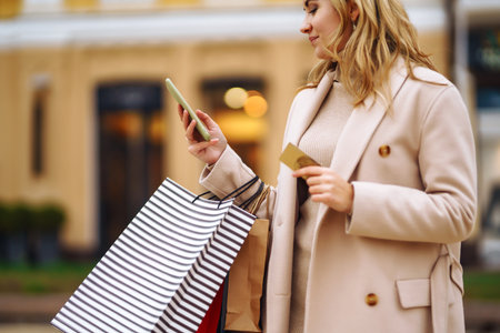 Beautiful blonde holding shopping bags on the street. Hand of woman with multi-coloured bags.の写真素材