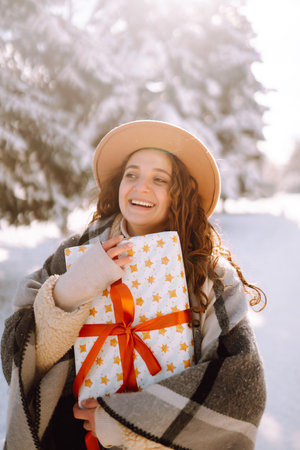 Pretty Woman holding a giftbox with red ribbon in the winter park. Happy winter time. new year's.の写真素材