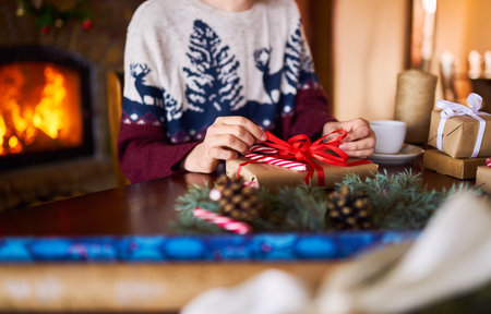 Men's hands hold Christmas present. Man using ribbon, green fir tree twig to create Christmas gift.の写真素材