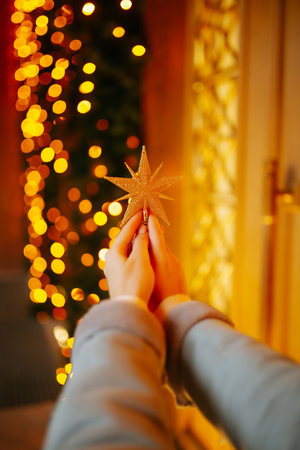Young woman drinking hot coffee while walking in Christmas market decorated with holiday lights.の写真素材
