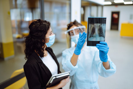 A female doctor in visor and protective gloves discussing an x-ray. Doctor examines an X-ray.の写真素材