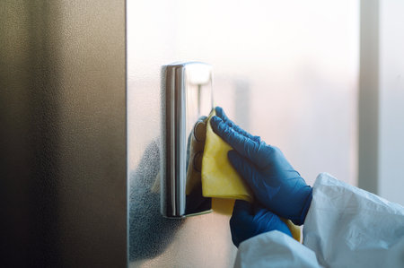 Man in Hazmat suit, protective gloves and goggles use sprayer equipment disinfect the entrance.の写真素材